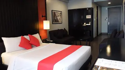 a hotel room with a large white bed with red pillows at Amelie Hotel Manila in Manila