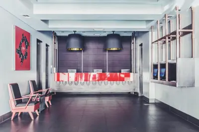 a restaurant with a red counter and chairs in a room at Amelie Hotel Manila in Manila