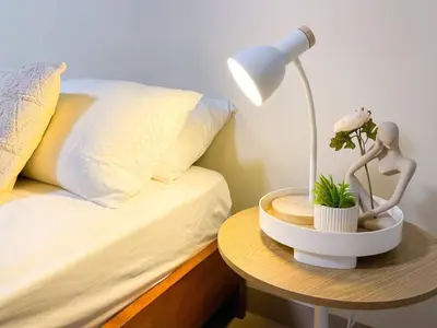 a bed with a table with a lamp and a plant at Cozy Bgc Stay Near Uptown Mall & Hyatt #ournw24l in Manila
