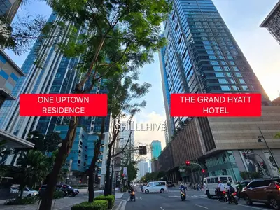 two red signs on a city street with buildings at Bgc Prime, Near Uptown Mall, Grand Hyatt #ournw7m in Manila