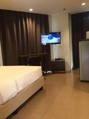 a hotel room with a bed and a flat screen tv at Spacious Studio Apartment B203 in Manila