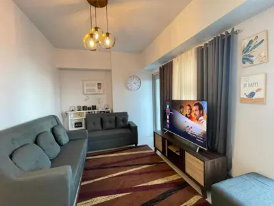 a living room with a couch and a flat screen tv at Staycation near SLMEC, US Embassy and Supreme Court in Manila