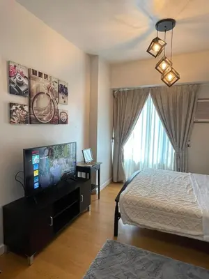 a bedroom with a bed and a flat screen tv at Condo in Ermita near UP-PGH, St Lukes & US Embassy in Manila