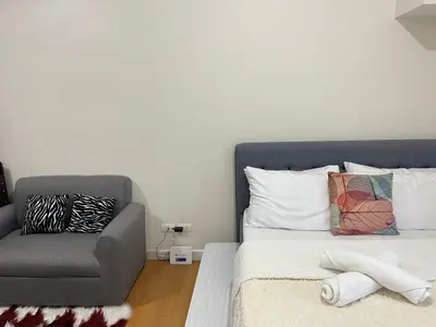 a bedroom with a bed with a chair and a pillow at Condo in Ermita near UP-PGH, St Lukes & US Embassy in Manila