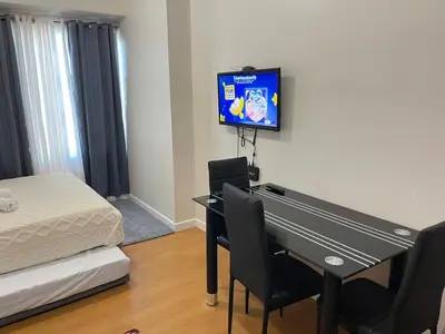 a room with a desk with a bed and a tv on the wall at Condo in Ermita near UP-PGH, St Lukes & US Embassy in Manila