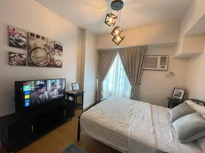 a bedroom with a bed and a flat screen tv at Condo in Ermita near UP-PGH, St Lukes & US Embassy in Manila