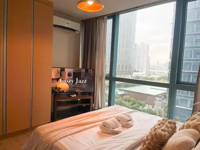 a bedroom with a bed and a large window at Cozy Stay In Bgc Near Uptown Mall #oursw11d1 in Manila