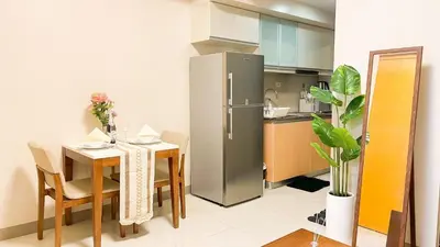 a kitchen with a table and a stainless steel refrigerator at Luxury BGC Condo, Steps to Uptown Mall #oursw31i in Manila