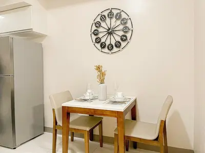 a dining room table and chairs with a clock on the wall at Prime Bgc Stay Near Uptown, Grand Hyatt #oursw18j in Manila
