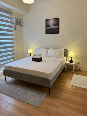 a bedroom with a bed with a television on the wall at K&K The Modern Crib at Holland Park Condo Southwoods City in Biñan