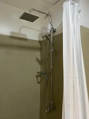 a shower with a shower head next to a shower curtain at D'Shore to Relax Shore Residences MOA PASAY in Manila