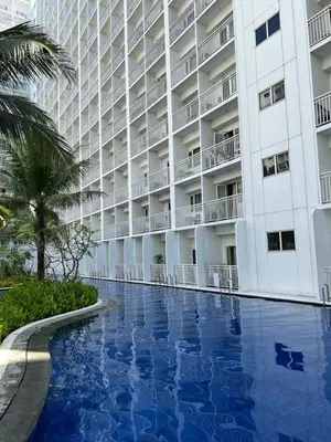 a hotel with a swimming pool in front of a building at D'Shore to Relax Shore Residences MOA PASAY in Manila