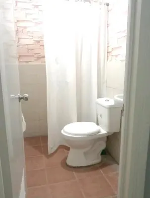 a bathroom with a toilet and a white shower curtain at Gorgeous 2BR Condo unit with free WiFi in Imus