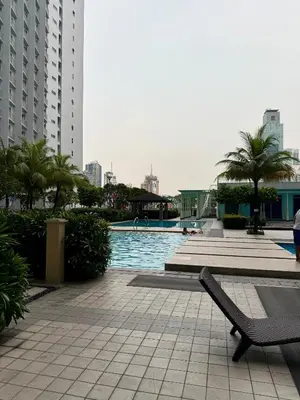 a swimming pool in a city with palm trees and buildings at Serene Suite In Jazz Residences in Manila