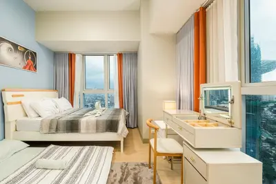 a bedroom with a bed and a sink and a mirror at BGC 2BR Uptown Parksuites with balcony and bathtub in Manila