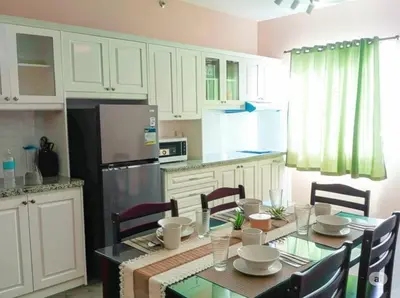 a kitchen with a table with chairs and a refrigerator at Urban Zen in Calamba