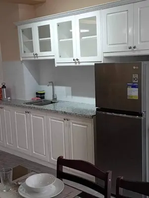 a kitchen with white cabinets and a black refrigerator at Urban Zen in Calamba