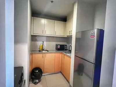 a small kitchen with white cabinets and a refrigerator at EG Private House -BGC UPTOWN in Manila