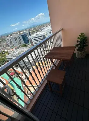 a balcony with a wooden table and bench on a balcony at Amazing Sunrise Venice Grand Canal Balcony, Xbox Series X console with Game Pass Ultimate, FREE coffee, Pool, Gym & Sauna, 5 mins to BGC in Manila
