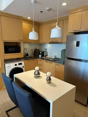 a kitchen with a table and a refrigerator at Amazing Sunrise Venice Grand Canal Balcony, Xbox Series X console with Game Pass Ultimate, FREE coffee, Pool, Gym & Sauna, 5 mins to BGC in Manila