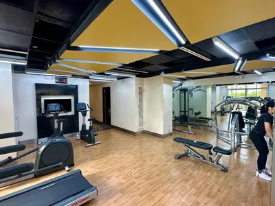 a gym with cardio equipment and a woman on a treadmill at Amazing Sunrise Venice Grand Canal Balcony, Xbox Series X console with Game Pass Ultimate, FREE coffee, Pool, Gym & Sauna, 5 mins to BGC in Manila