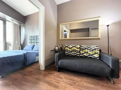 a bedroom with a bed and a mirror and a couch at 1BR with Balcony KL Tower, Greenbelt near AIM in Manila