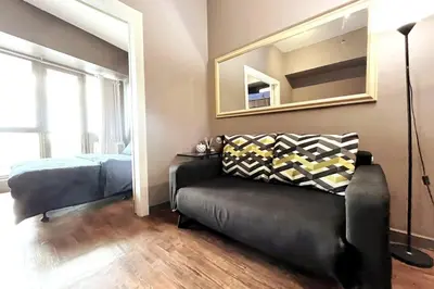 a bedroom with a couch and a bed and a mirror at 1BR with Balcony KL Tower, Greenbelt near AIM in Manila