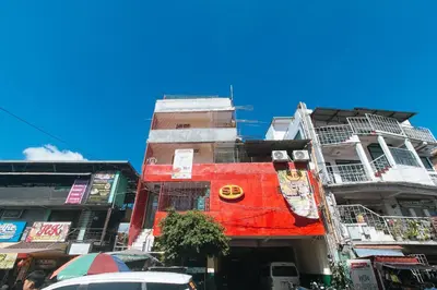 a tall building on a city street with cars at RedDoorz @ Western Bicutan Transients Inn in Manila