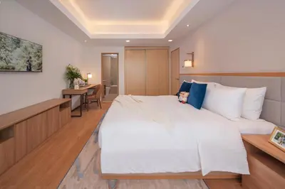 a bedroom with a large white bed and a desk at Somerset Valero Makati in Manila