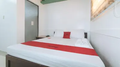 a bedroom with a white bed with a red blanket at RedDoorz @ Moss Hotel Dasmarinas in Cavite