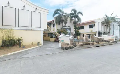 a street in front of a building with palm trees at RedDoorz @ Moss Hotel Dasmarinas in Cavite