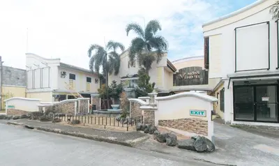 a building with palm trees in front of a street at RedDoorz @ Moss Hotel Dasmarinas in Cavite