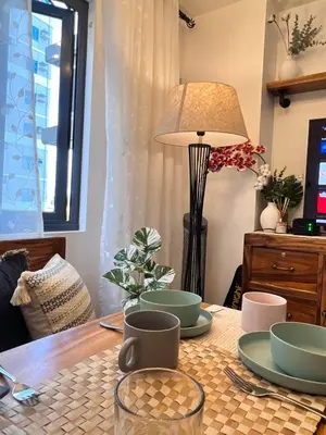 a table with plates and cups and a lamp at SMDC Green 2 Staycation, The Traditional & Modern Fusion Condo in Pasong Bayog