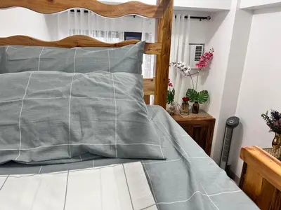 a bed with a gray quilt on it at SMDC Green 2 Staycation, The Traditional & Modern Fusion Condo in Pasong Bayog