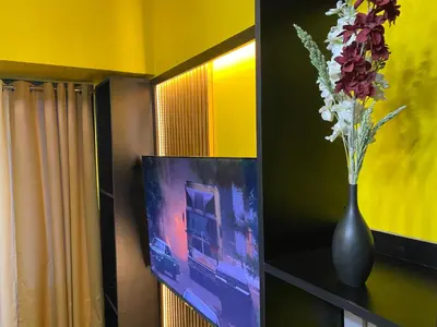 a vase with flowers on a table next to a television at Laugh and Lounge 2 Bedroom Luxury Condo Air residence Makati in Manila