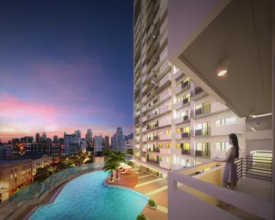 a woman standing on the balcony of a building with a pool at Cookies Nest at 100West Makati in Manila