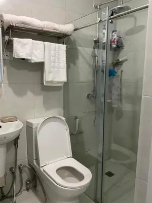 a bathroom with a toilet and a glass shower at Cookies Nest at 100West Makati in Manila