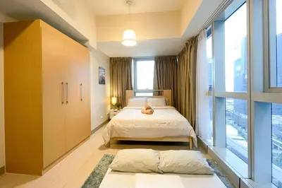 a bedroom with a bed and a large window at BGC 3BR Uptown Parksuites with bathtub 16 in Manila
