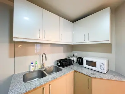 a kitchen with white cabinets and a sink and a microwave at BGC 3BR Uptown Parksuites with bathtub 16 in Manila