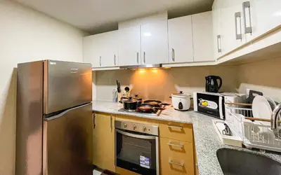a kitchen with white cabinets and a stainless steel refrigerator at BGC 2BR Uptown Parksuites with PS4 43 in Manila