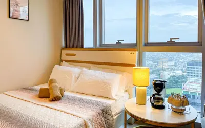 a bedroom with a bed and a table with a lamp at BGC 2BR Uptown Parksuites with PS4 43 in Manila
