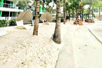 a beach with palm trees and chairs and umbrellas at Azure 1BR citylights with netlfix near airport in Manila