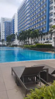 a bench next to a swimming pool with a large building at S Residences in Manila