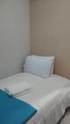 a white bed with a pillow and a blue blanket at S Residences in Manila