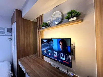 a flat screen tv on a wall with a clock at Casa Del Hasmin in Puting Kahoy