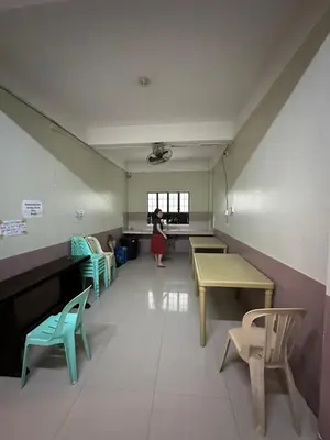 a woman standing in a room with tables and chairs at St John's Pearl Transient House in Manila