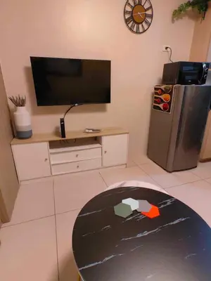 a living room with a television and a refrigerator at Condo Near MOA, NAIA, PICC, & CCP that is comfy with a view! in Manila
