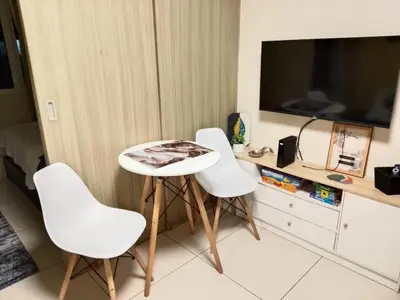 a room with three white chairs and a table and a tv at Condo Near MOA, NAIA, PICC, & CCP that is comfy with a view! in Manila