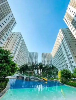 a swimming pool in the middle of two tall buildings at California Suite - by GUEST RESERVATION'S MANILA in Manila
