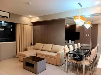 a living room with a couch and a glass table at California Suite - by GUEST RESERVATION'S MANILA in Manila